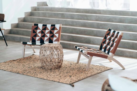 Stylish indoor scene featuring modern chairs and a woven basket table on a textured rug.