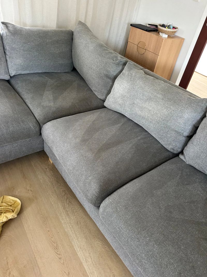 Corner view of grey upholstered couch with cushions, showcasing clean and comfortable seating area.
