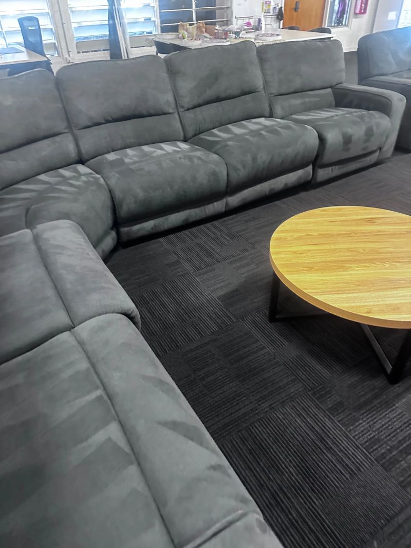 Upholstered sectional couch in a business environment with a wooden coffee table.
