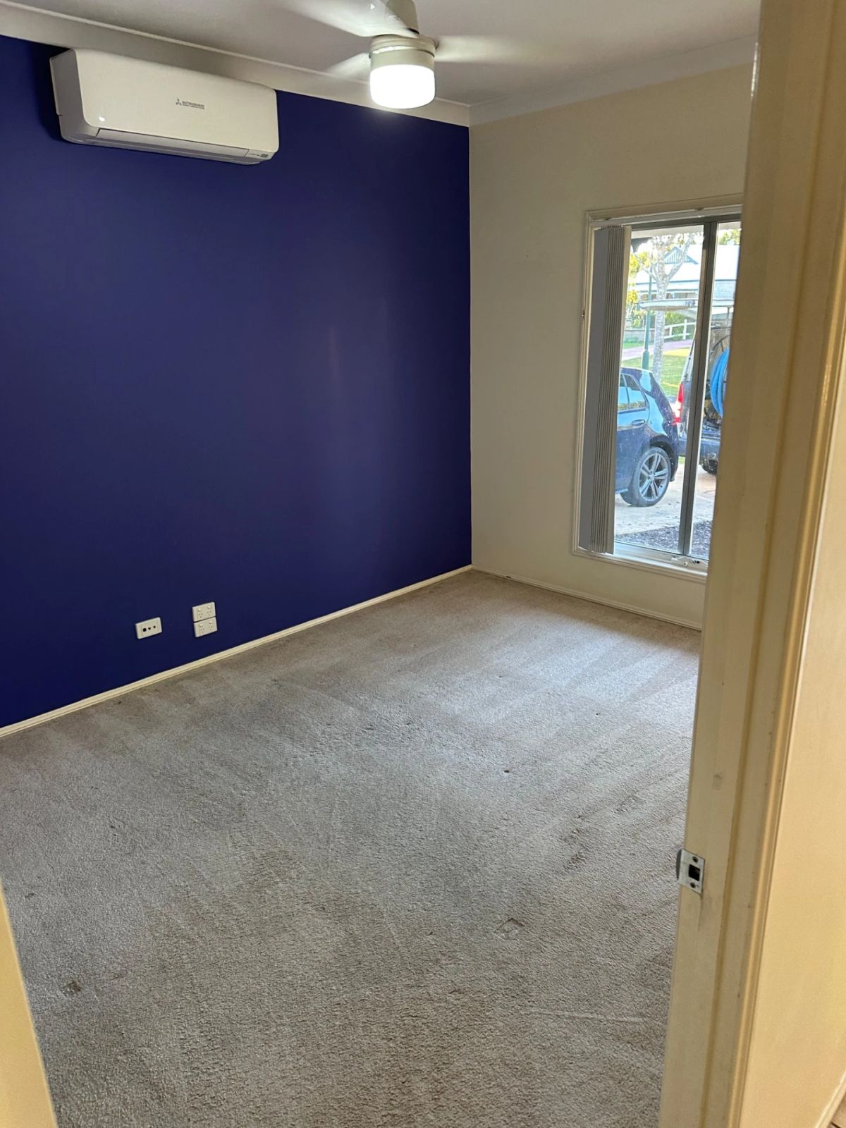 Clean room with beige carpet and blue accent wall, ready for carpet cleaning services